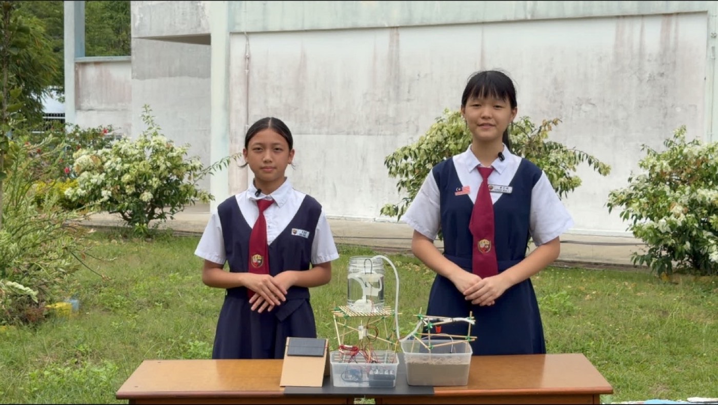 Kathleen and Althea with the full system outdoors: solar panel, controller box, soil sensor tub and the bamboo water tower